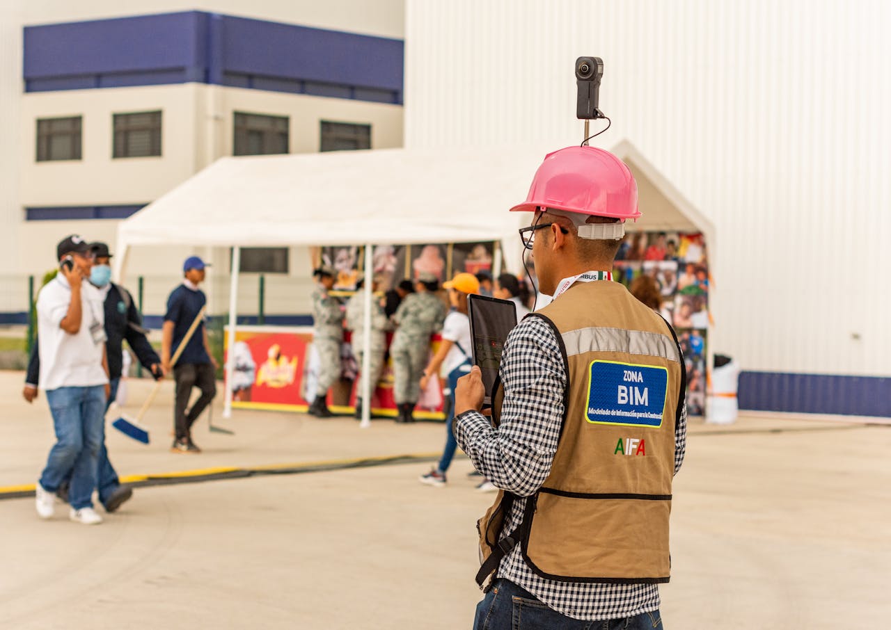 A construction worker with a tablet and camera inspects a site, using modern technology for documentation.