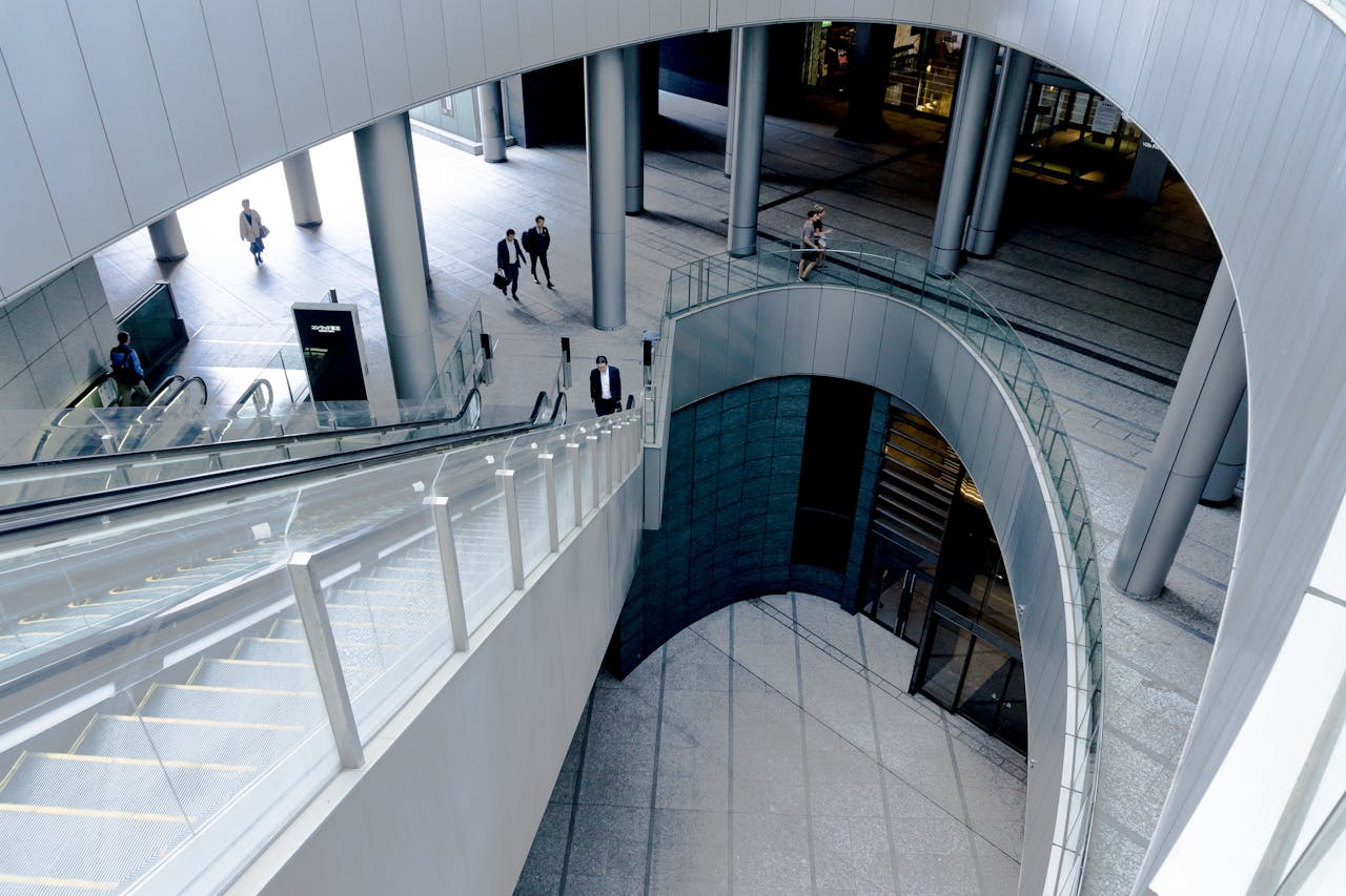 Dynamic architectural shot of a modern building interior featuring an escalator and business people.