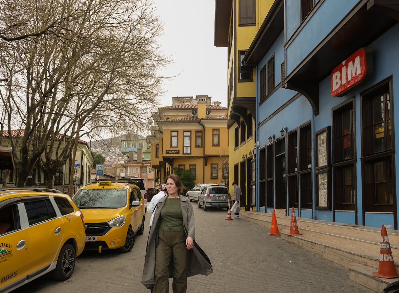 A lively street with yellow taxis, colorful buildings, and pedestrians in an urban setting.
